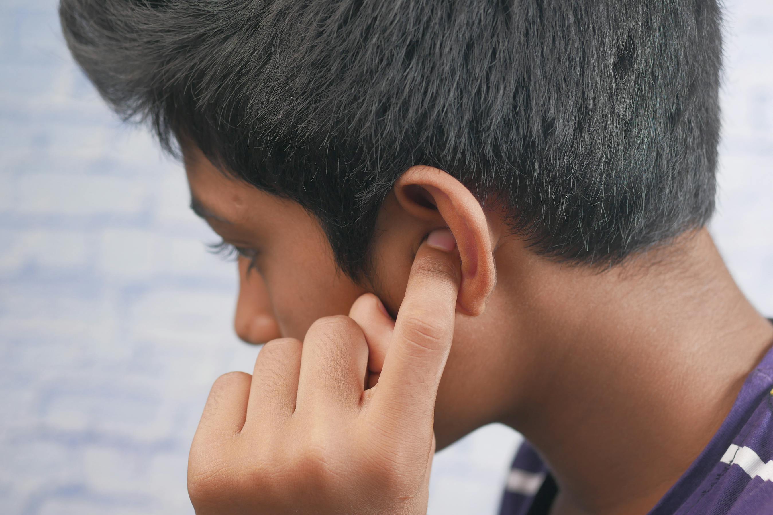 Personne couvrant son oreille, illustrant la gêne provoquée par les acouphènes