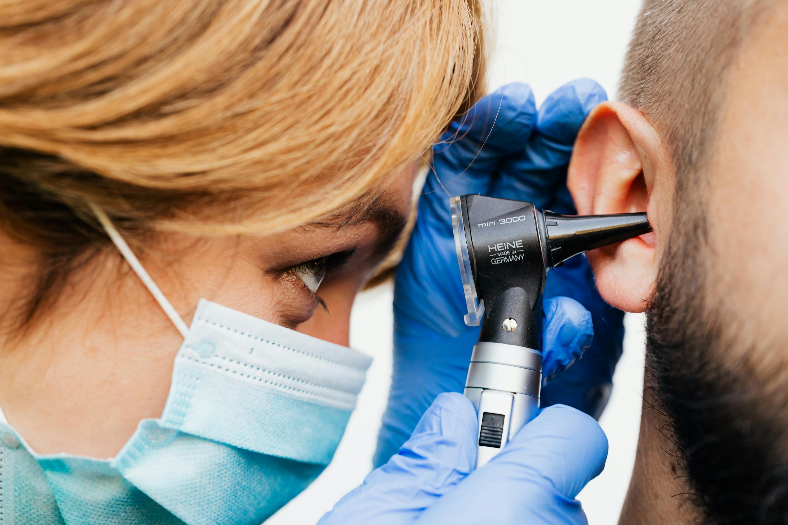 Audioprothésiste réalisant un examen de l'oreille avec un otoscope lors d'un bilan auditif