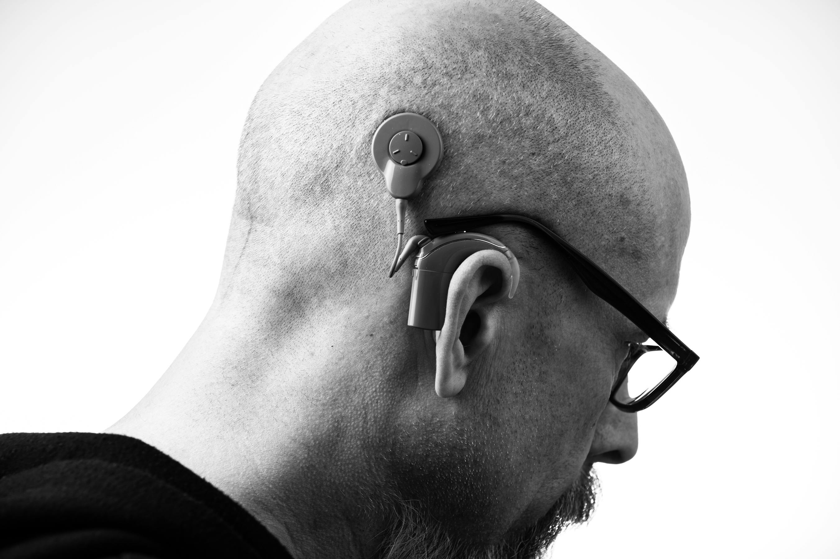 Portrait d'un homme portant un appareil auditif moderne et des lunettes